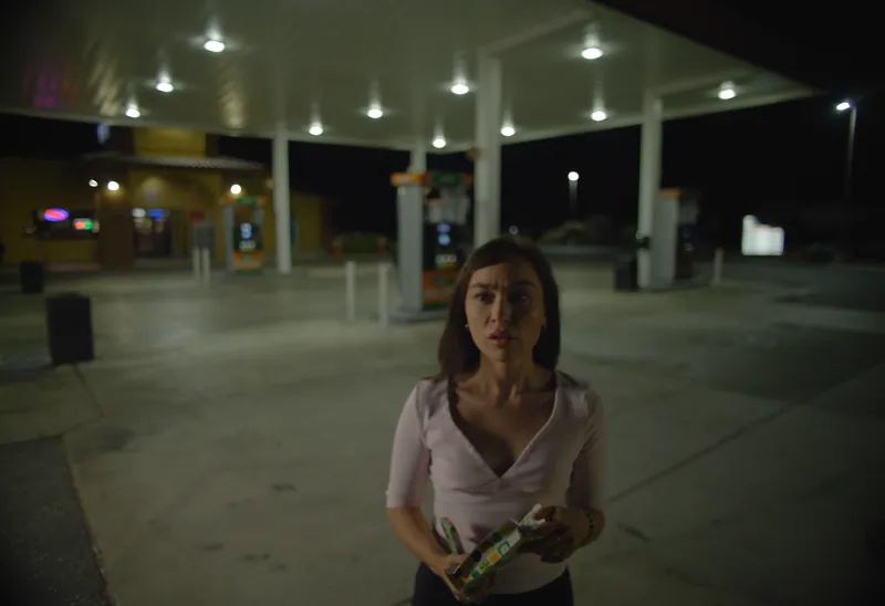 Still from Walkers: a woman alone at a desert gas station at night